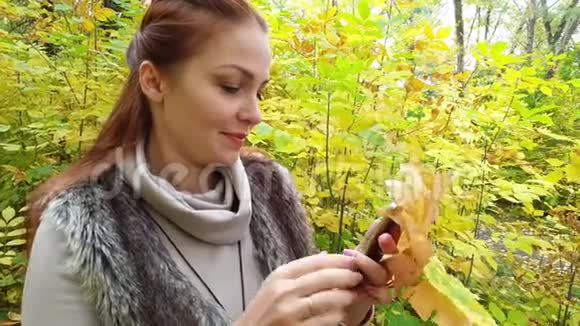 秋天公园的迷人女子带着电话视频的预览图