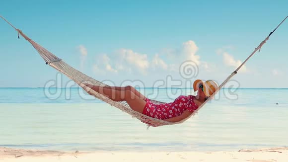 女人在热带岛屿海滩的吊床上放松暑假的异国情调视频的预览图