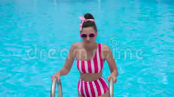穿着条纹粉色泳衣的年轻女孩潜入游泳池视频的预览图