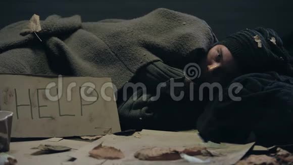 在船上有帮助标志的无家可归的人躺在肮脏的地方冻得发抖视频的预览图