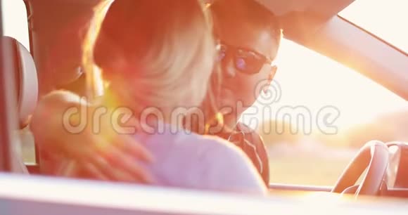 戴墨镜的男人坐在车里亲吻女人视频的预览图
