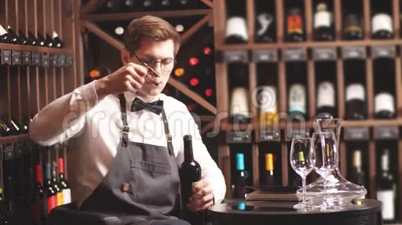 优雅的年轻侍酒师在葡萄酒精品店用蝴蝶结解开一瓶葡萄酒视频的预览图