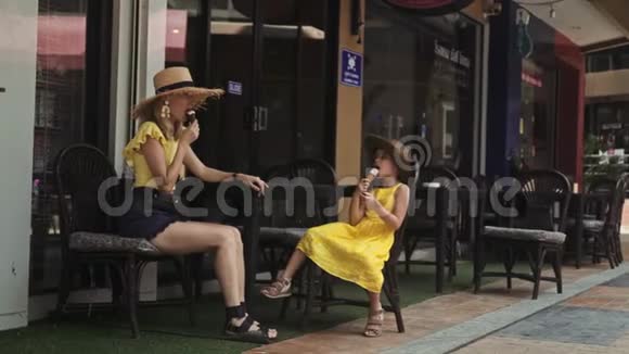 母亲和女儿在夏日的街头咖啡馆吃冰淇淋视频的预览图