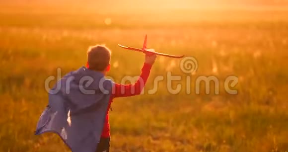 那个男孩在日落时手里拿着一架飞机跑过田野视频的预览图