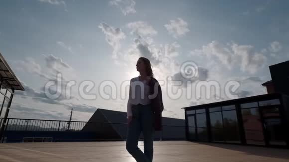 一位年轻女子在天空和云彩背景上的剪影城市里一个女孩的肖像视频的预览图