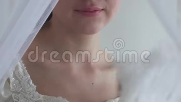 年轻漂亮的嘴唇和肩膀穿着白色婚纱的女人女孩在白色背景上挥舞着羽毛扇视频的预览图