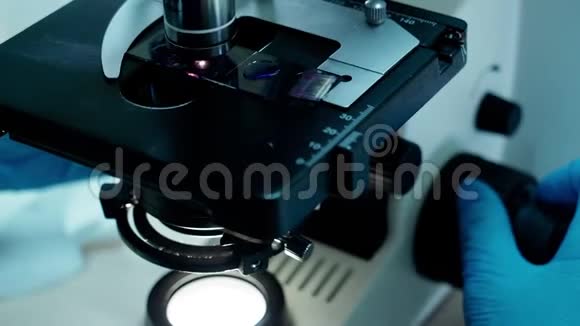 双手在实验室用显微镜研究生物化学材料视频的预览图