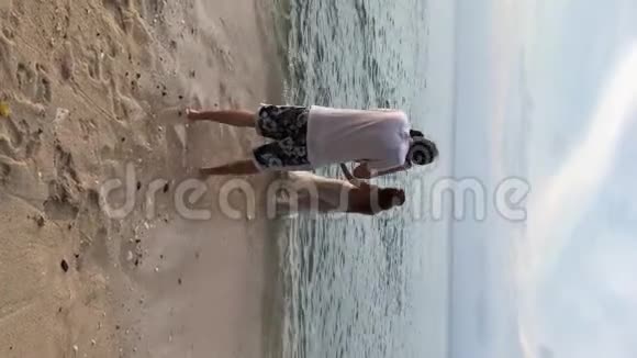 垂直视频摄影师为新娘和新郎在海边散步拍照假期婚礼视频的预览图