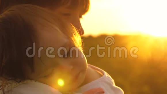 小孩子在夕阳的温暖光线下睡在小妈妈的怀里女儿和妈妈对着夜空慢慢视频的预览图