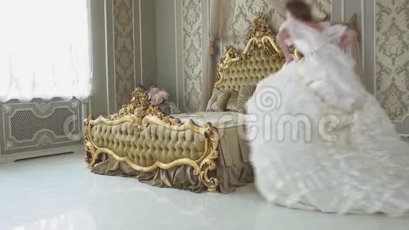 穿着长球袍的年轻女子跑着摔倒在金色装饰的床上视频的预览图