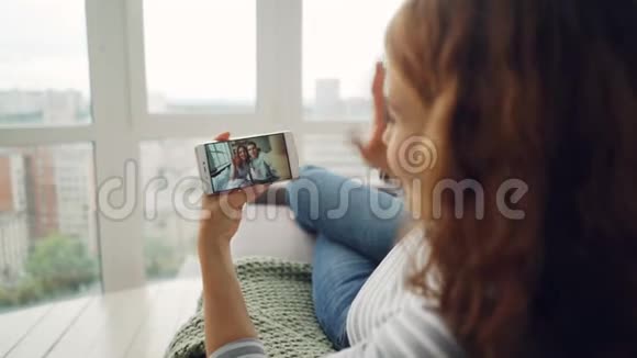 年轻的女士和朋友聊天用智能手机看屏幕然后看漂亮的一对视频的预览图