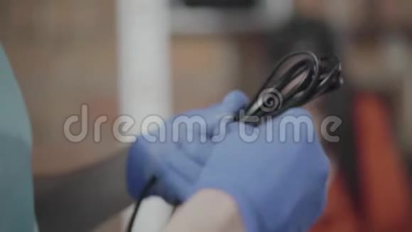 男工程师在女同事的背景下在车间里用蓝色手套卷黑色电缆特写镜头视频的预览图