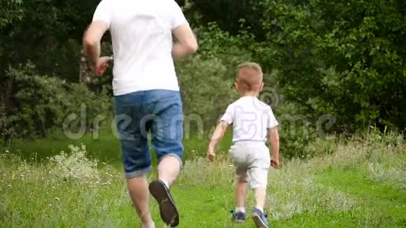 幸福家庭父子俩在公园的绿草上奔跑春夏户外游乐视频的预览图