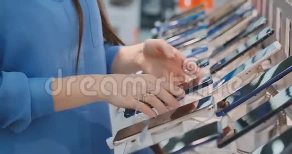 一名女子手中握着一部新智能手机靠近一家电子商店的店面视频的预览图