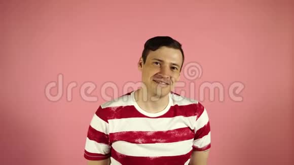 站在粉红色背景下微笑和困惑的男人视频的预览图