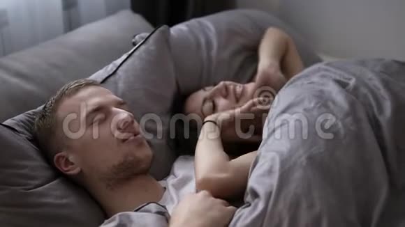 年轻的黑发女朋友正在早上叫醒她的男朋友或丈夫一起在床上玩得开心灰灰视频的预览图