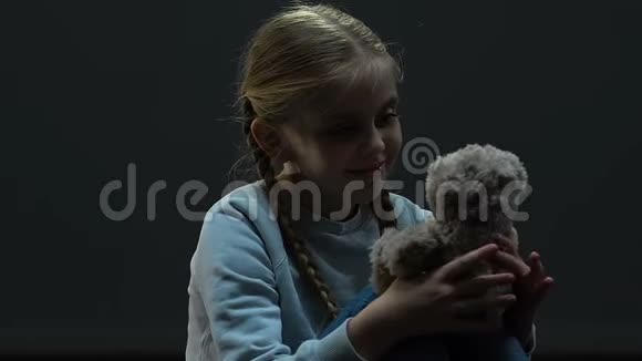 小女孩坐在黑暗中玩玩具熊家庭虐待虐待视频的预览图