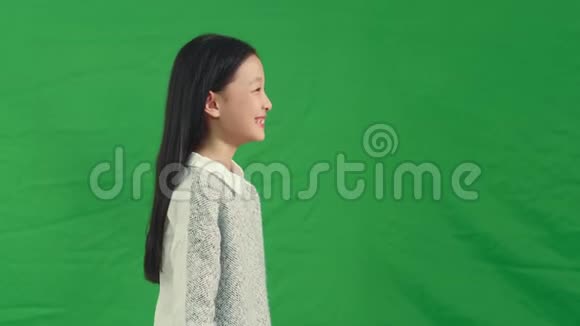 在绿色背景下微笑的亚洲女孩视频的预览图