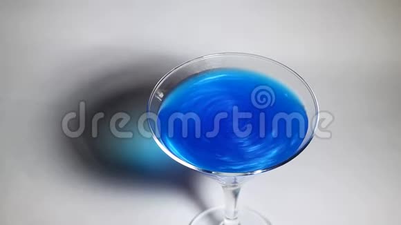 蓝色饮料在鸡尾酒中搅拌在玻璃酒杯里视频的预览图