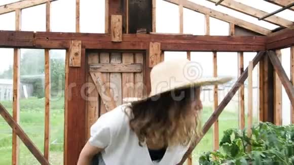 穿着草帽和草裙的女农民去温室享受收获视频的预览图