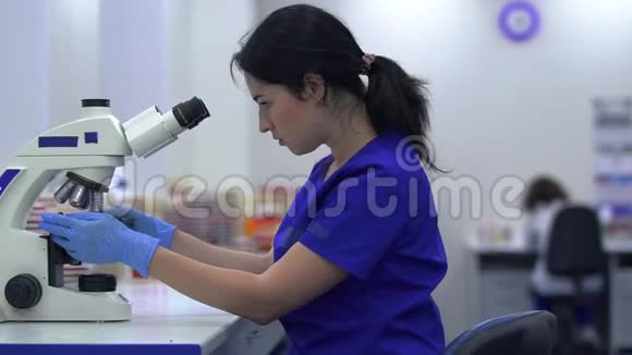 肖像实验室助理在实验室看显微镜视频的预览图