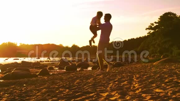 父亲在海边和儿子玩耍日落或日出的暖色有爱心的父母和美丽的孩子爱情视频的预览图