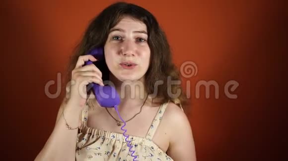 女人在橙色背景下打电话女执话筒座机电话女人在说话视频的预览图