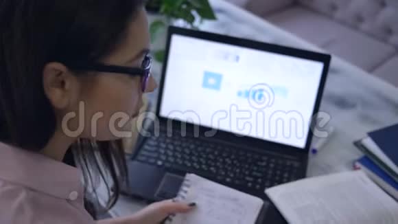 在电子教育期间学生女孩用笔记本画一个图表坐在一张桌子上在咖啡馆里放着书和笔记本电脑视频的预览图