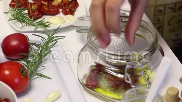 一个女人把干西红柿放进装有橄榄油盐和香料的罐子里视频的预览图
