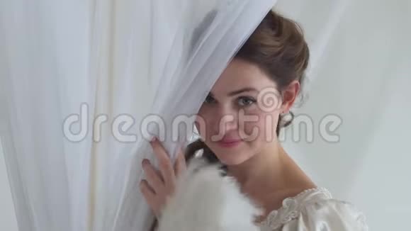 这是一个年轻害羞爱玩的女人穿着老式的球服戴着白色的面纱手里拿着羽毛扇子视频的预览图