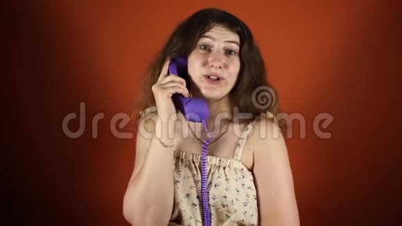 女人在橙色背景下打电话女执话筒座机电话女人在说话视频的预览图