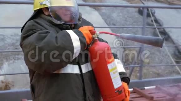 女消防员戴着防护头盔制服在烧烤架上用灭火器扑灭火焰消防队员视频的预览图