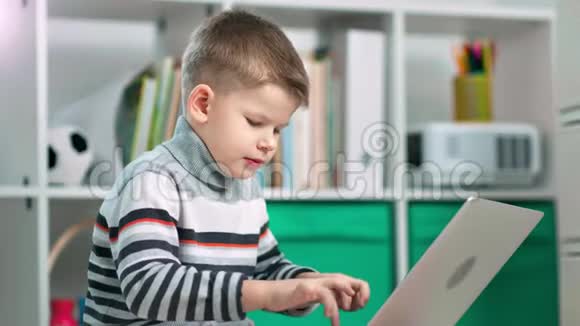 一个学龄前的男孩正在家里用笔记本电脑学习一些东西视频的预览图