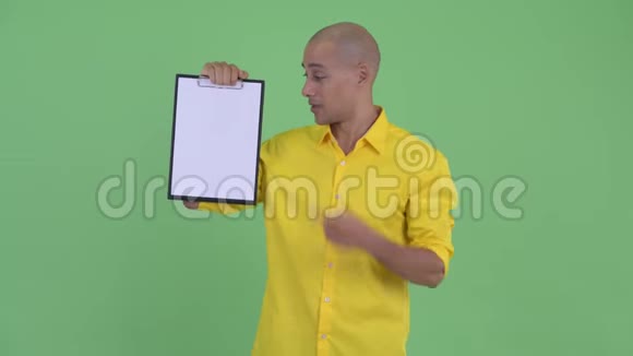 快乐英俊的秃头商人展示剪贴板竖起大拇指视频的预览图
