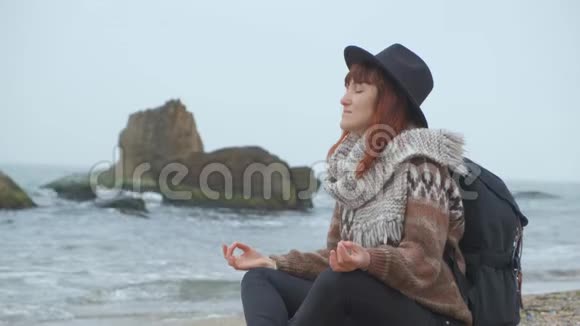在凉爽的秋日穿着温暖衣服的女孩在海边放松视频的预览图