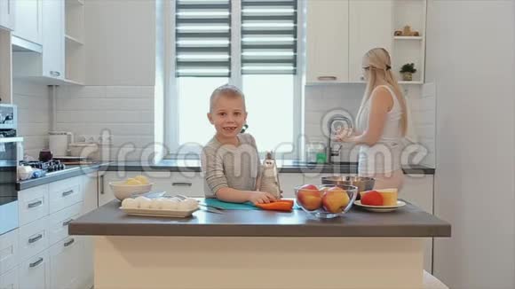 小帅哥在桌子上擦胡萝卜一位年轻美丽的白种人母亲留着一头白发儿子在一个视频的预览图