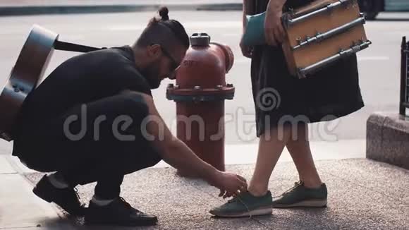 带吉他的男人在街上女孩的鞋子浪漫创意情侣近红色消防栓插头爱和关心4K视频的预览图