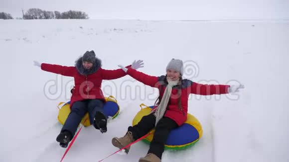 女孩们在白色的雪道上去雪碟开心地笑着寒冷的冬天快乐的少年们视频的预览图