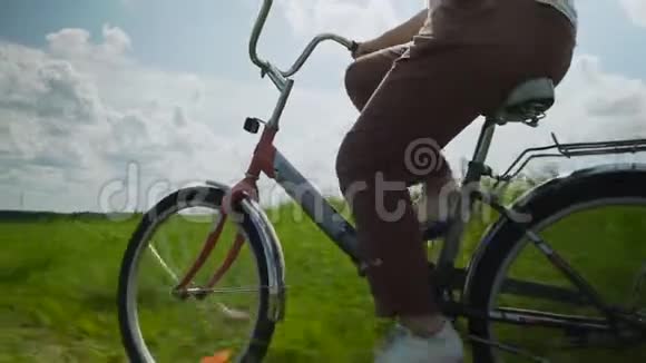 女孩骑着红色自行车穿过绿色的田野视频的预览图