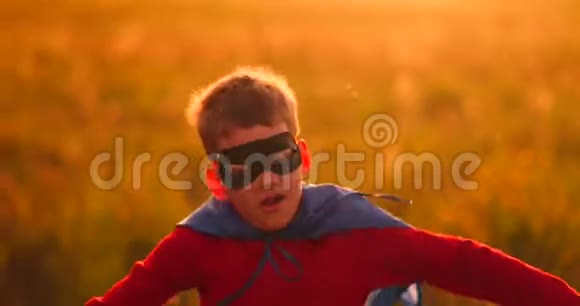 穿着超级英雄服装和面具的男孩在日落时跑过田野梦想着幻想视频的预览图