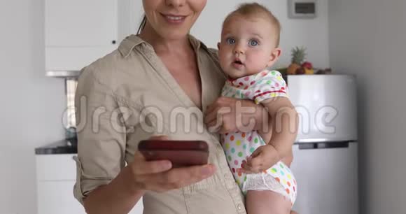 作物母亲带着婴儿使用智能手机视频的预览图