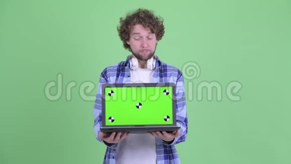 快乐的年轻有胡子的时髦男人一边说一边展示笔记本电脑视频的预览图