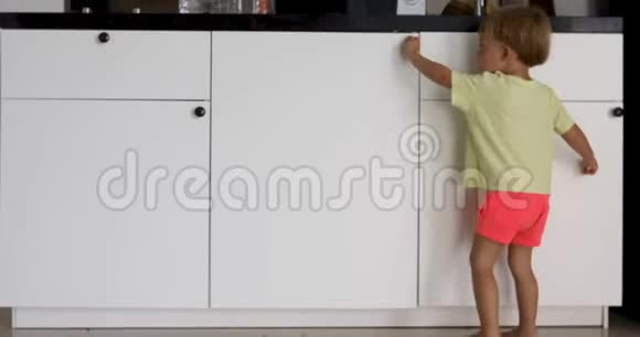 小男孩在厨房橱柜里看视频的预览图