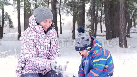 幸福家庭妈妈和儿子在冬天白雪覆盖的森林或公园里玩人们体验到情感视频的预览图