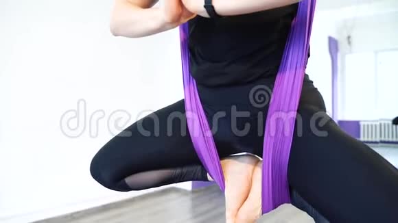 在健身俱乐部的紫色吊床上练习空中瑜伽的年轻美女吊床上飞舞蝴蝶式视频的预览图