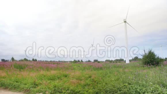 人类在风力涡轮机能源生产的背景下走过田野全速射击视频的预览图
