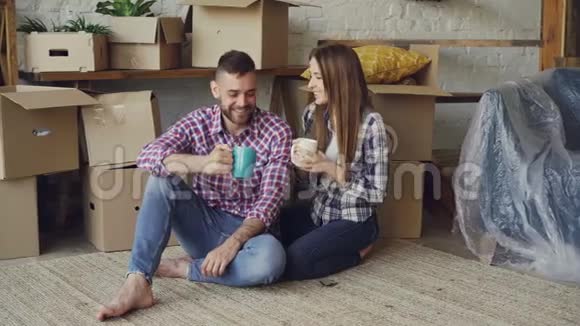 新婚夫妇同居后他们在新公寓的地板上着杯子喝茶视频的预览图