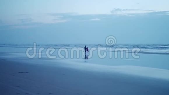 日落时分男人和孕妇沿着海滨散步的剪影4K视频的预览图
