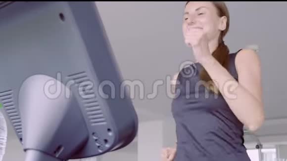 快乐微笑的女人在健身中心的健身房跑步机上跑步视频的预览图