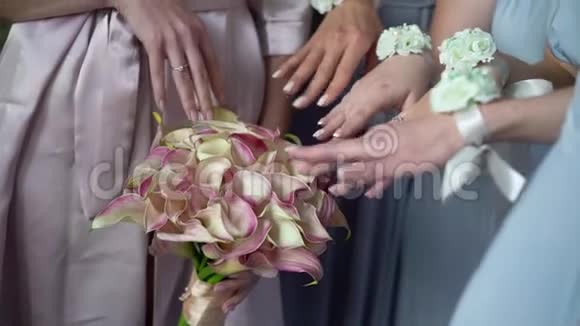 新娘和伴娘在婚礼上摆姿势戴着鲜花手镯的女孩手和戴着新娘花束的妻子视频的预览图